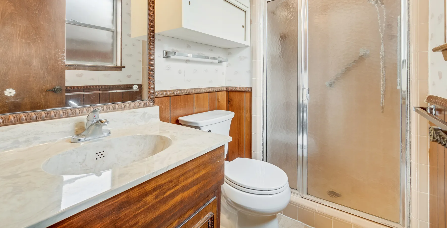 Outdated bathroom in Los Angeles with old vanity and worn shower before renovation